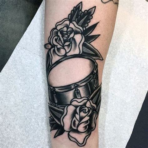 A Black And White Photo Of A Tattoo On The Arm With Roses Drums And An