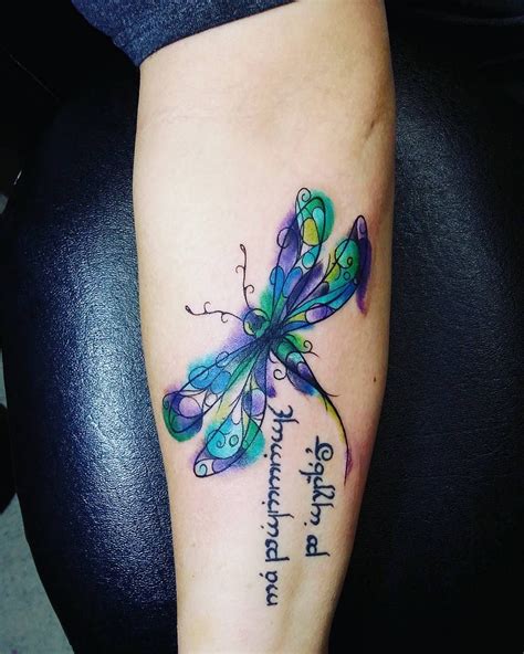 A Colorful Dragonfly Tattoo On The Right Arm And Leg With Words Written Below It