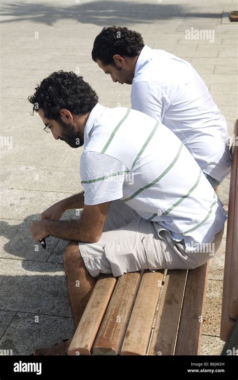 A Group Of Men Sitting Next To Each Other On Top Of A Bench