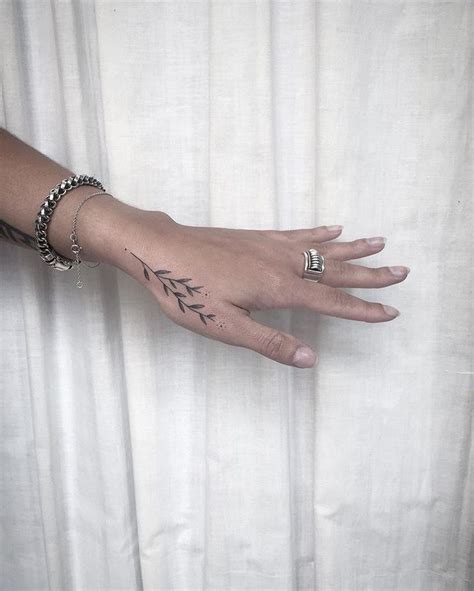 A Person S Hand With Tattoos And Rings On It Next To A Curtain